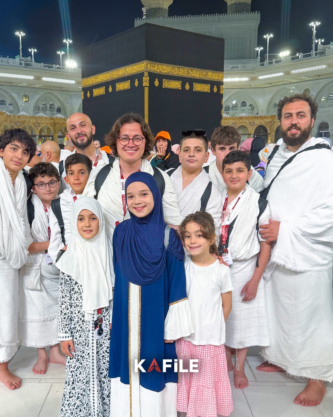 Kafile Turizm umre grubundaki çocuklar ve rehberler gece Kâbe önünde hatıra fotoğrafında